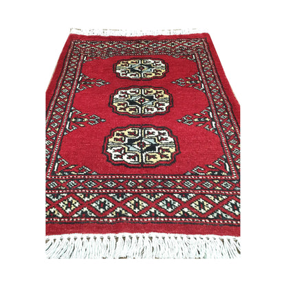 Red field and border detail of Afghan Bokhara wool rug showing three ivory gul medallions and traditional border pattern
