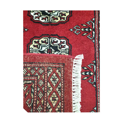 Folded corner detail of Afghan Bokhara wool rug showing the back of the rug, fringe and red front pattern