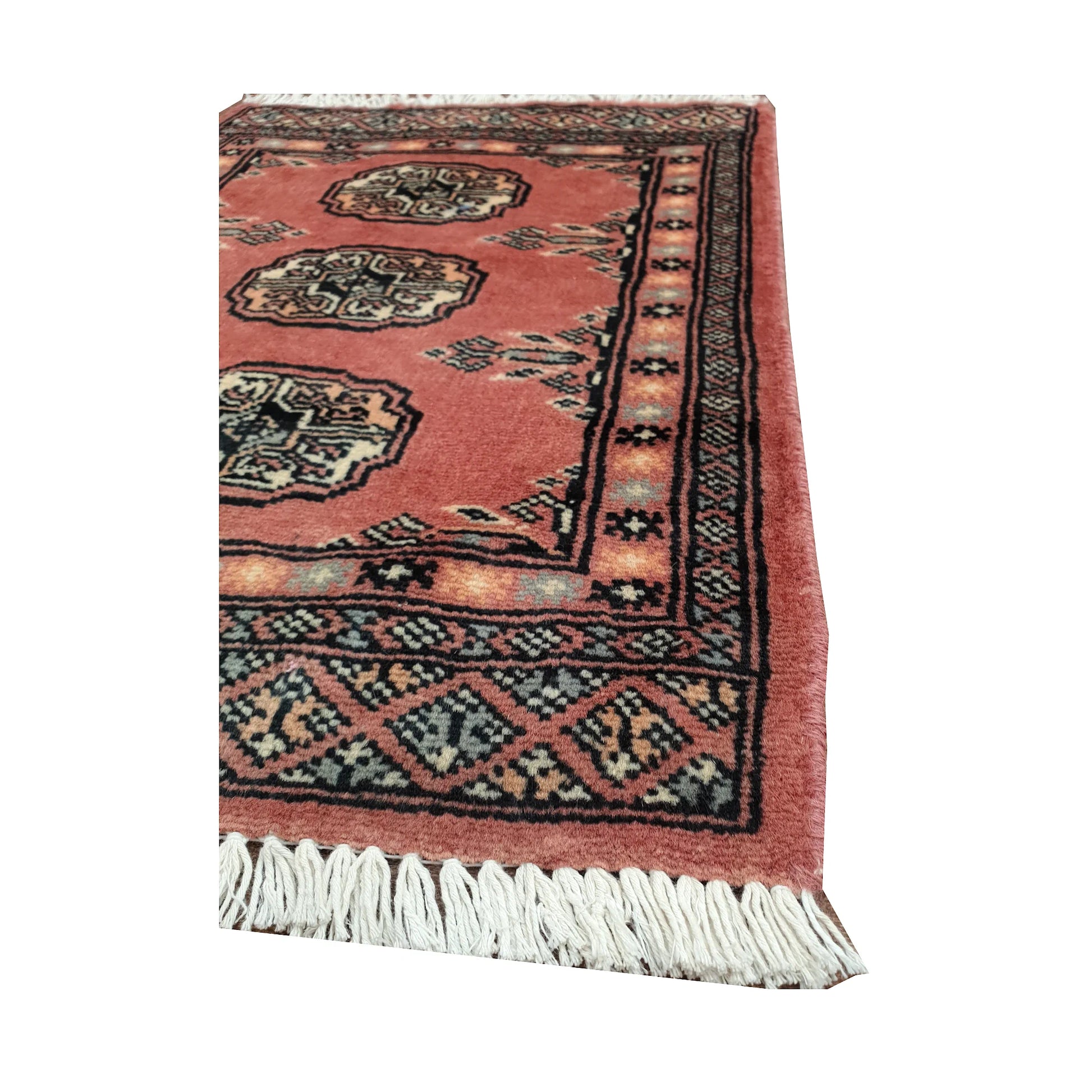 Angled fringe and border detail of Afghan Bokhara wool rug showing salmon red pile, ivory gul motifs and dark edging