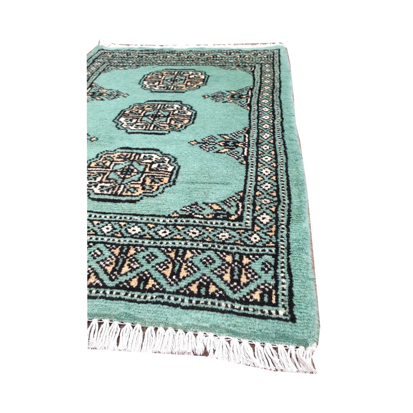 Angled fringe and border detail of Afghan Bokhara wool rug showing light turquoise pile, ivory gul motifs and dark edging