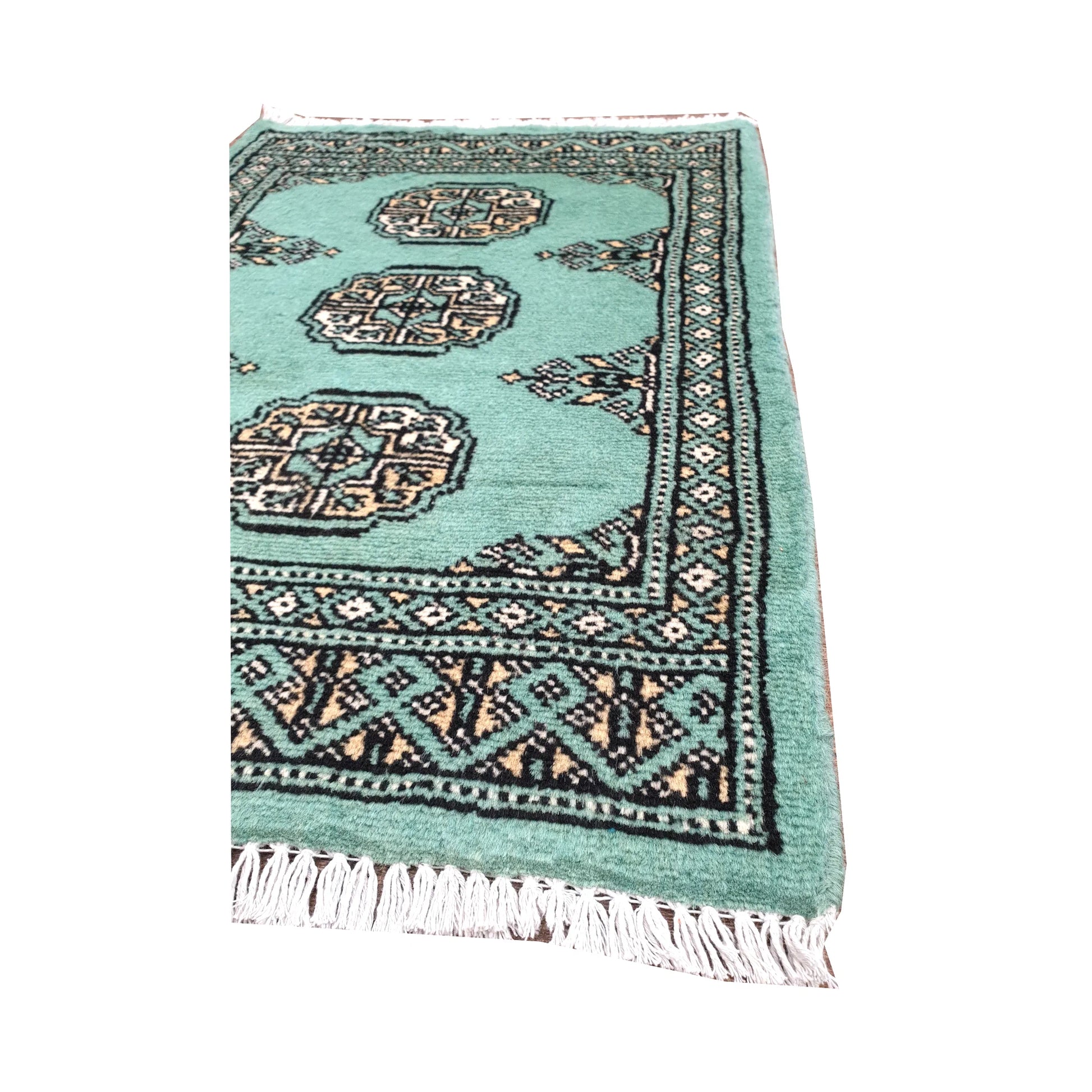 Angled fringe and border detail of Afghan Bokhara wool rug showing light turquoise pile, ivory gul motifs and dark edging