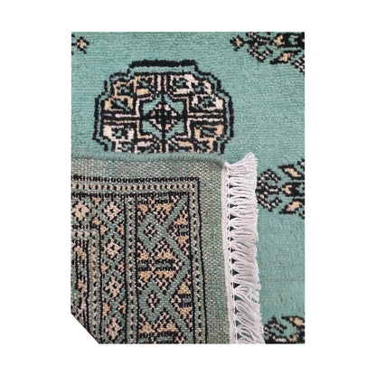 Folded corner detail of Afghan Bokhara wool rug showing the back of the rug, fringe and light turquoise front pattern