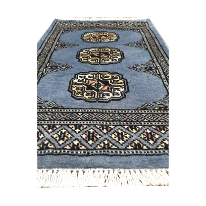 Blue-grey field and border detail of Afghan Bokhara wool rug showing three ivory gul medallions and geometric border