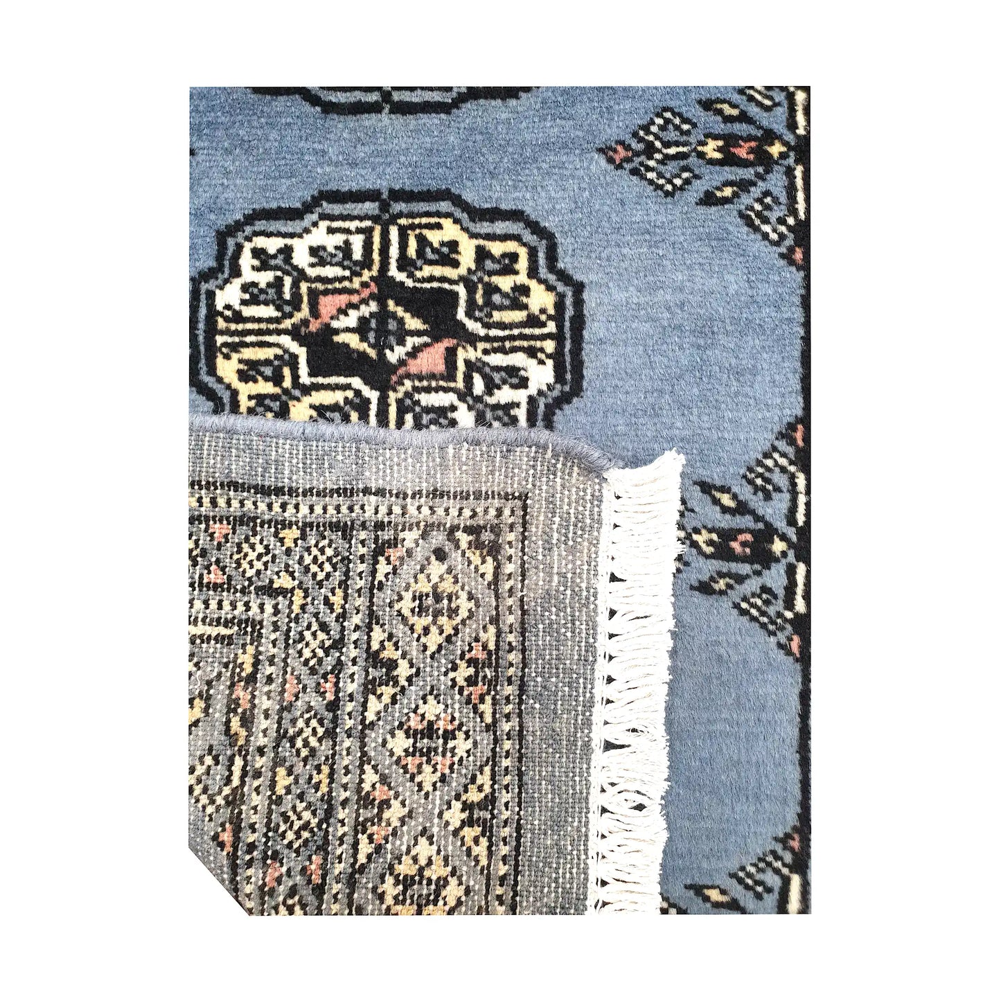Folded corner detail of Afghan Bokhara wool rug showing the back of the rug, fringe and blue-grey front pattern