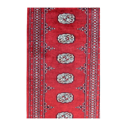 Field detail of Bokhara runner showing a row of ivory guls between patterned borders on a red ground