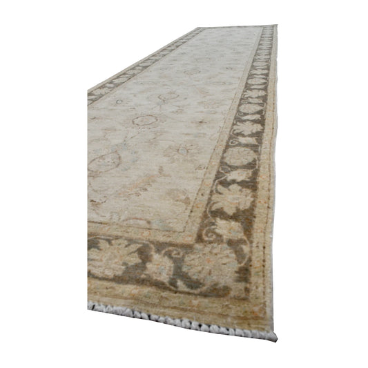 Angled view of Afghan Chobi runner showing its pale floral vines, taupe side border and fringed end