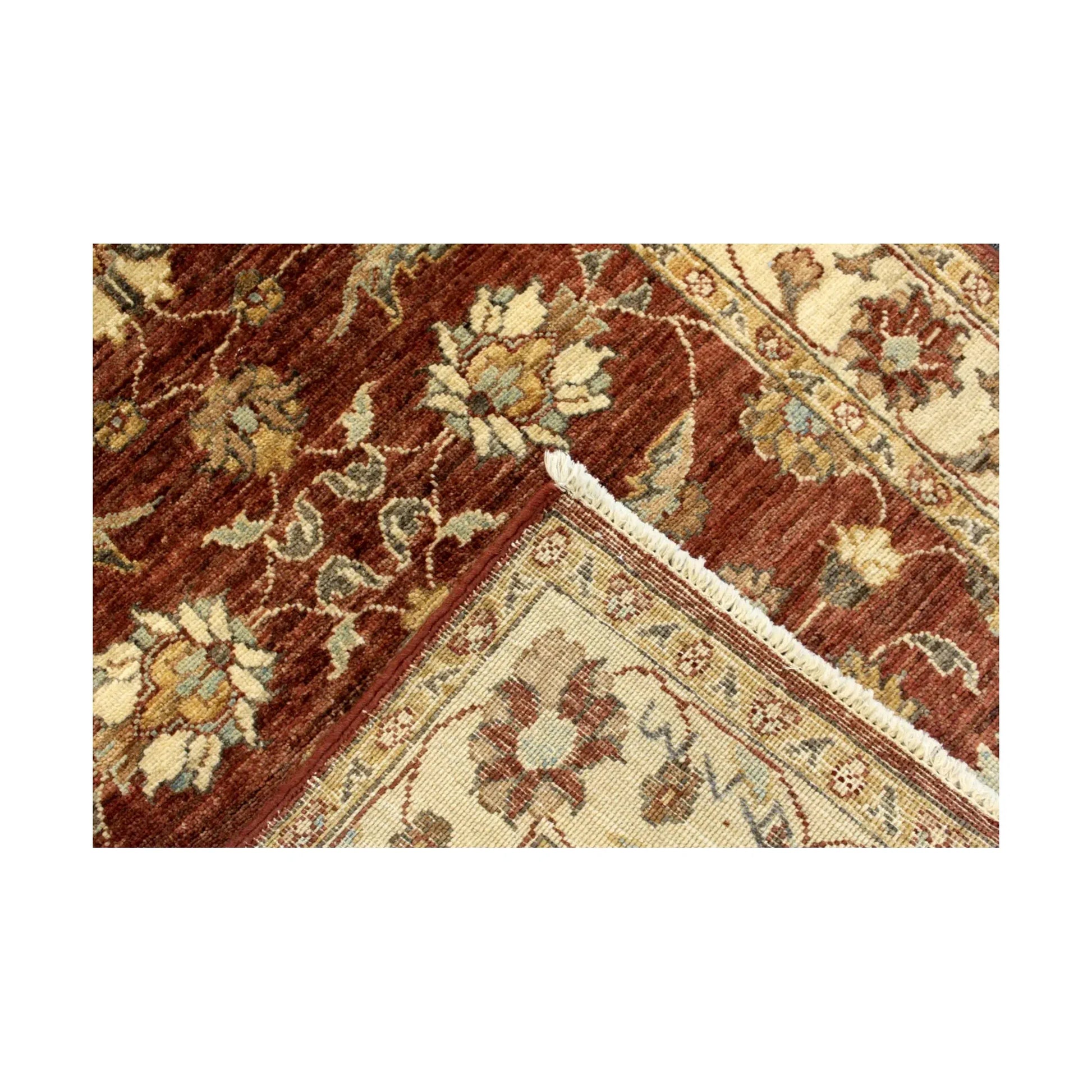 Folded edge showing the reverse weave, ivory fringe and floral border of the Afghan Chobi wool rug