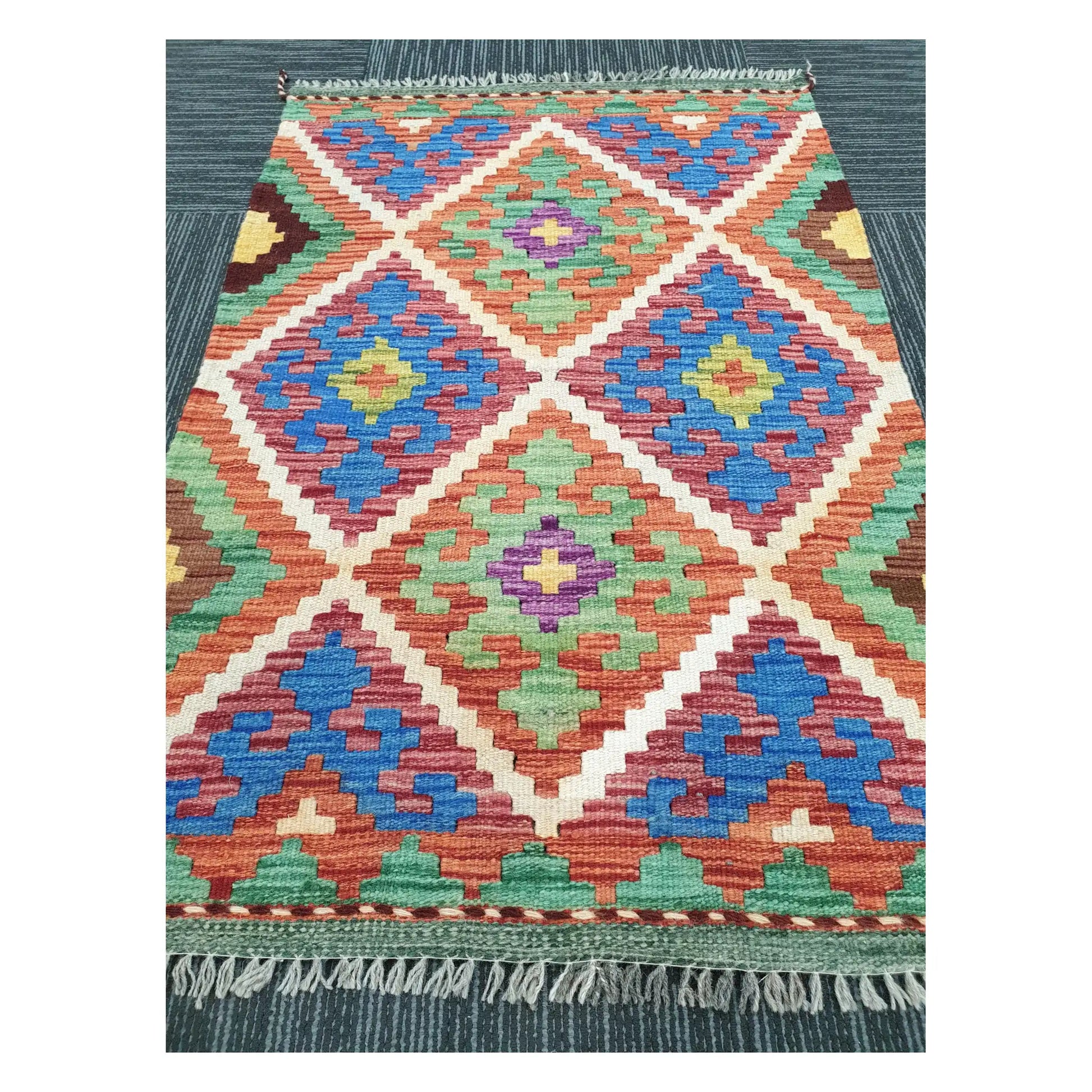 Angled view of Afghan Chobi Kilim flatweave rug showing geometric diamond trellis pattern, 100 x 65 cm