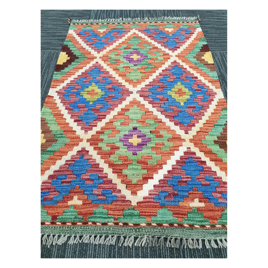 Angled view of Afghan Chobi Kilim flatweave rug showing geometric diamond trellis pattern, 100 x 65 cm