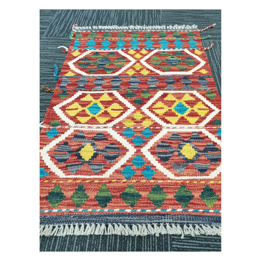 Angled view of Afghan Chobi Kilim flatweave rug showing geometric hexagon medallion pattern, 75 x 53 cm