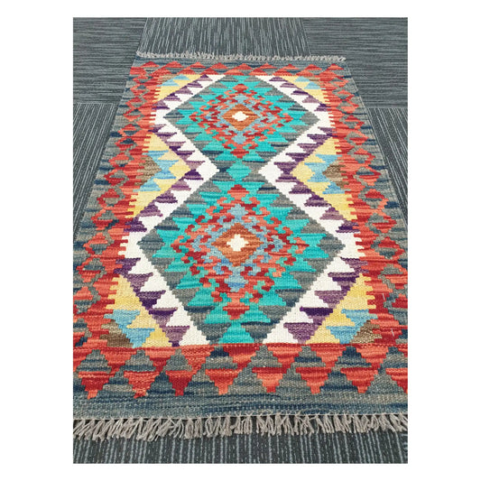 Angled view of Afghan Chobi Kilim flatweave rug showing geometric band pattern and centre diamond, 90 x 58 cm