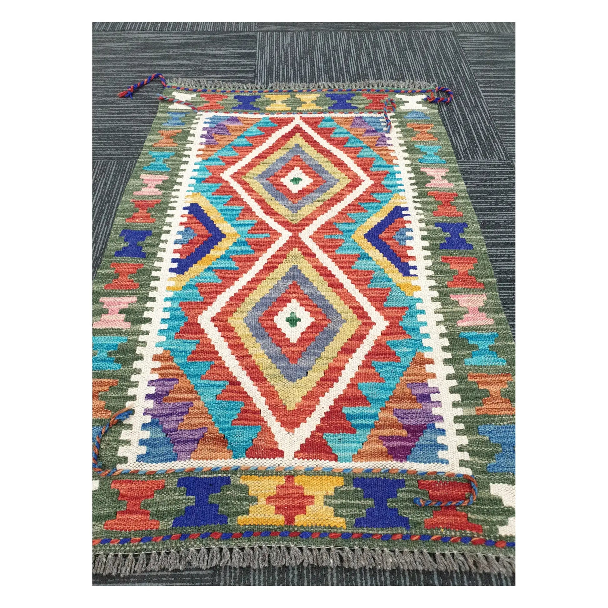 Angled view of Afghan Chobi Kilim flatweave rug showing elongated geometric diamond motif, 90 x 60 cm