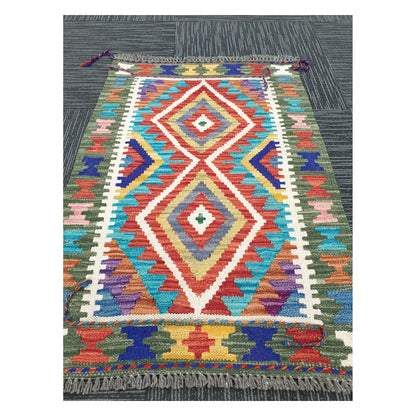 Angled view of Afghan Chobi Kilim flatweave rug showing elongated geometric diamond motif, 90 x 60 cm