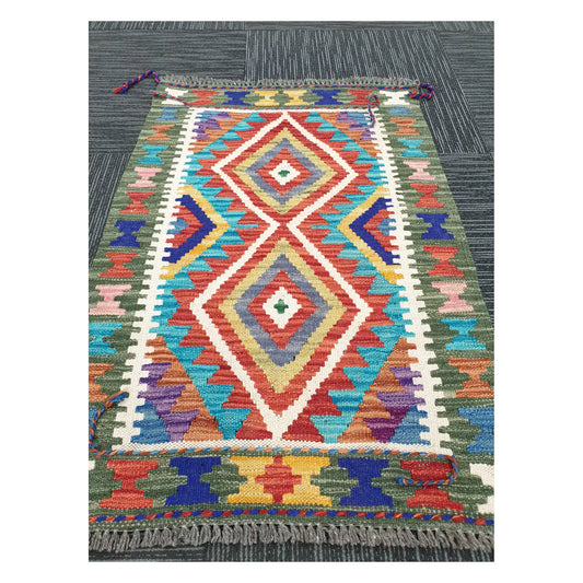 Angled view of Afghan Chobi Kilim flatweave rug showing elongated geometric diamond motif, 90 x 60 cm