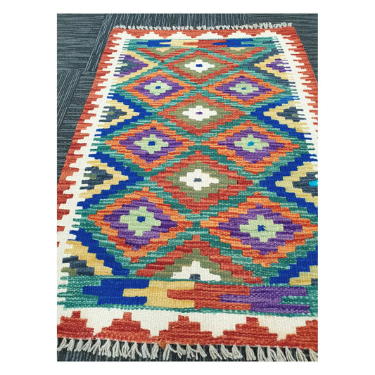 Angled view of Afghan Chobi Kilim flatweave rug showing multicolour diamond grid pattern, 90 x 60 cm