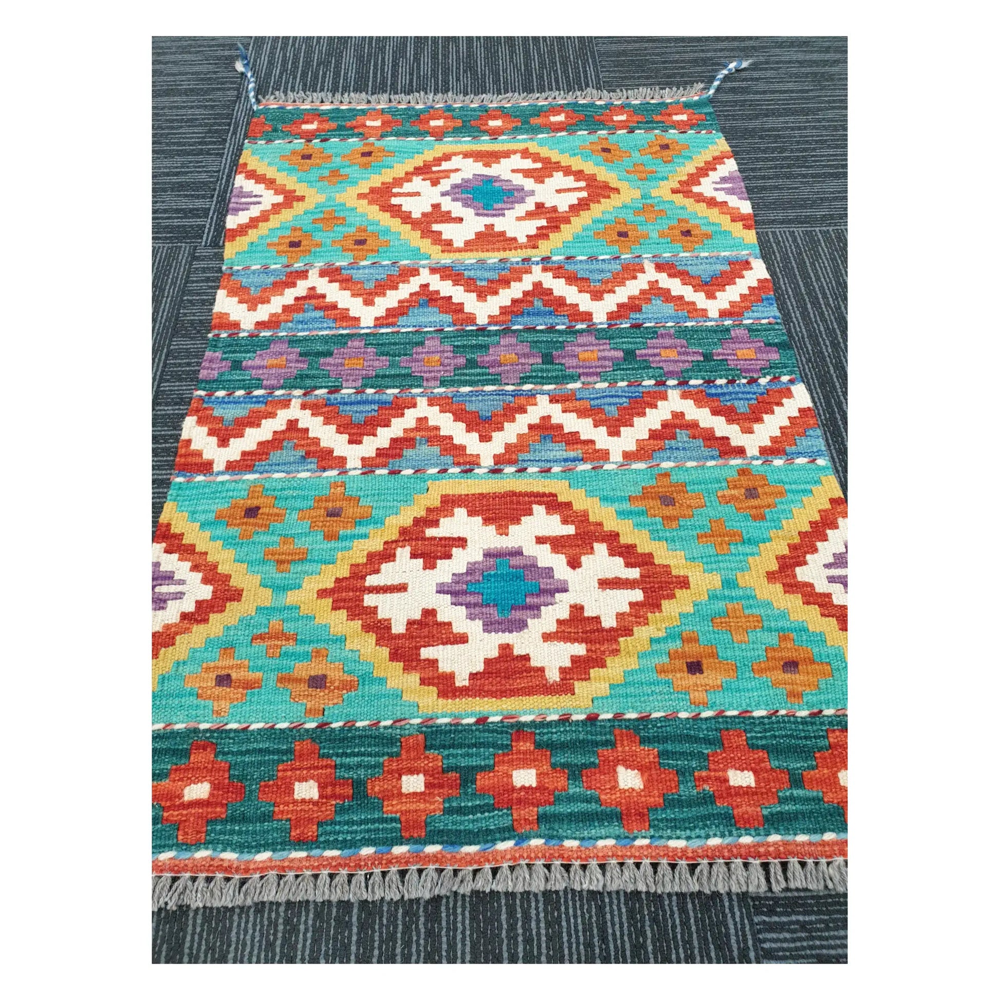 Angled view of Afghan Chobi Kilim flatweave rug showing geometric banded diamond pattern, 90 x 61 cm