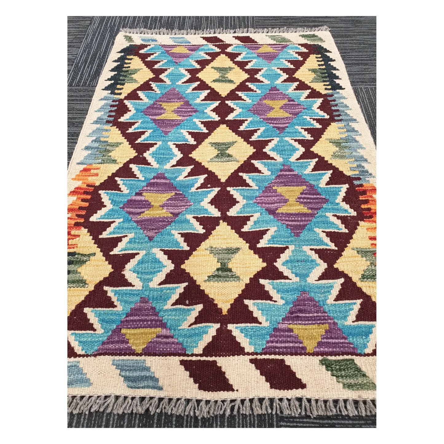 Angled view of Afghan Chobi Kilim flatweave rug showing linked diamond lattice pattern, 93 x 66 cm