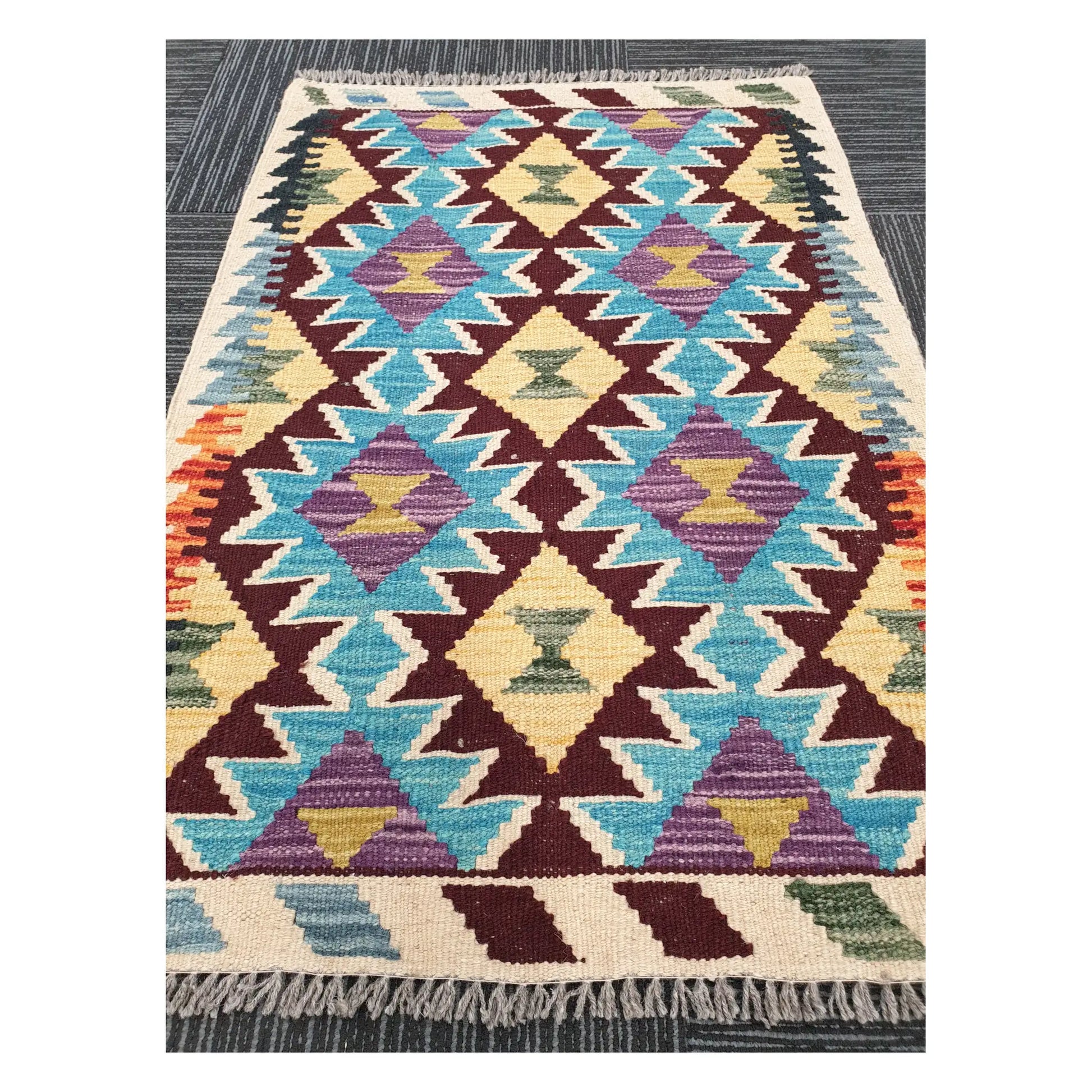 Angled view of Afghan Chobi Kilim flatweave rug showing linked diamond lattice pattern, 93 x 66 cm