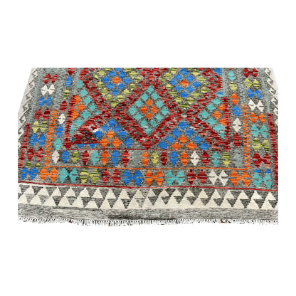 Fringe-end detail of Afghan Chobi Kilim rug showing blue and turquoise diamonds above layered geometric borders and an ivory triangle band.