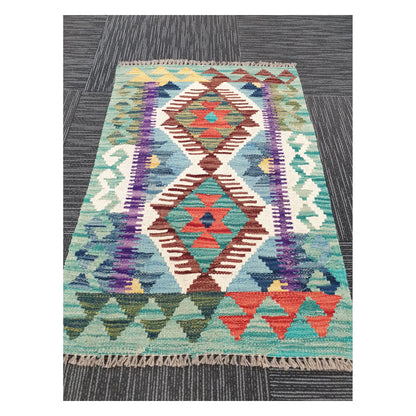 Angled view of Afghan Chobi Kilim rug showing twin-diamond motif and fringe, 88 x 59 cm