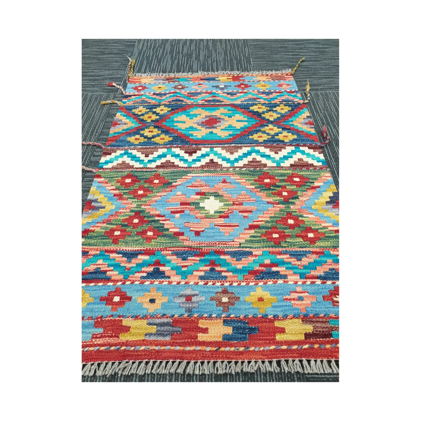 Angled view of Afghan Chobi Kilim rug showing bold geometric wool flatweave design, 96 x 62 cm