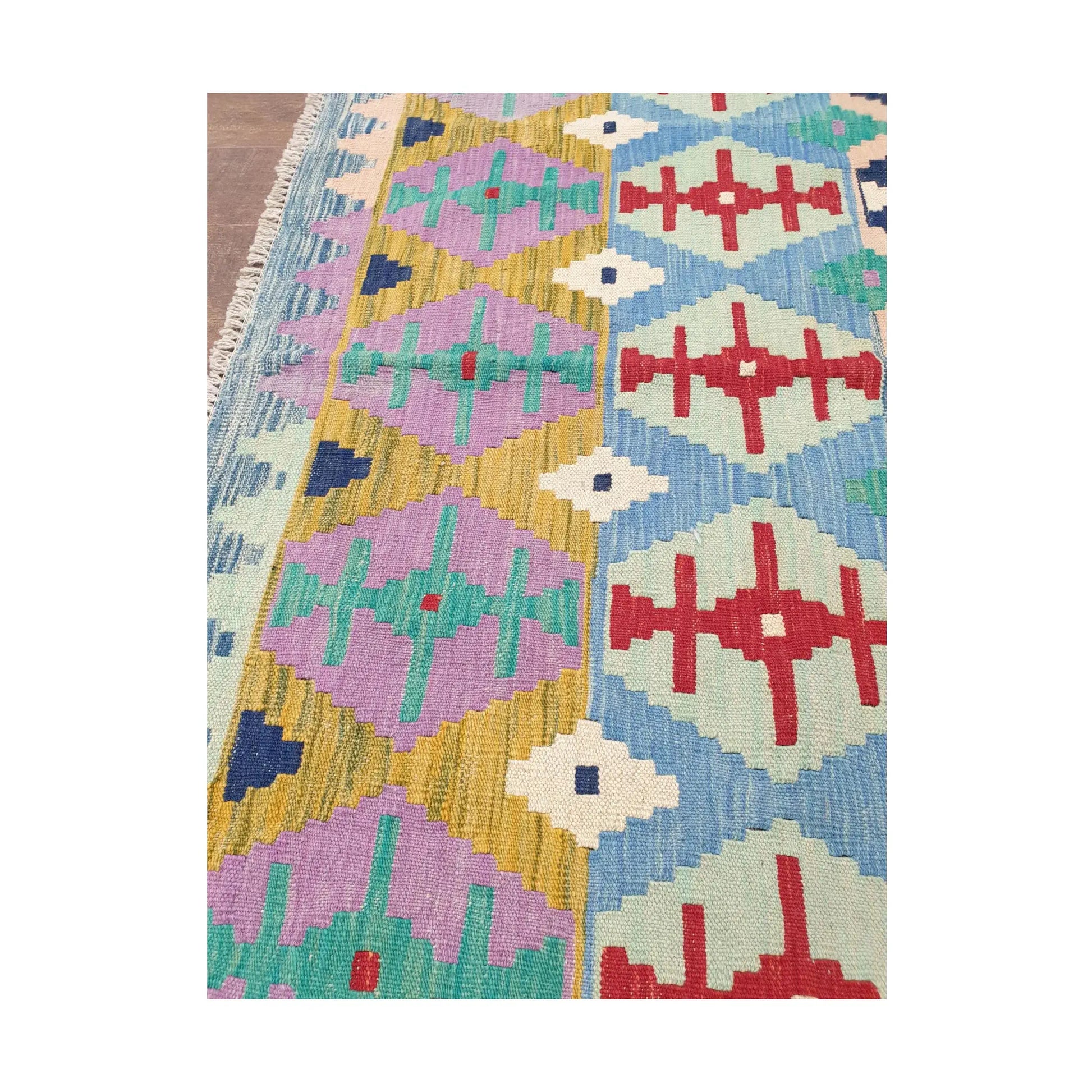 Side detail of Afghan Chobi Kilim pastel tribal rug showing aqua, red and ivory motifs
