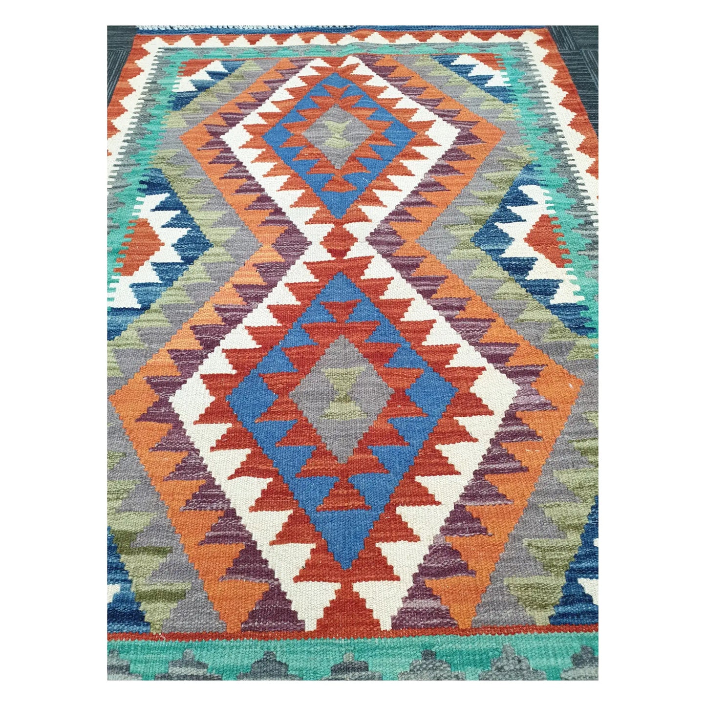 Close-up of Chobi Kilim rug with stacked medallions in terracotta, blue, teal, and ivory, 119 x 84 cm