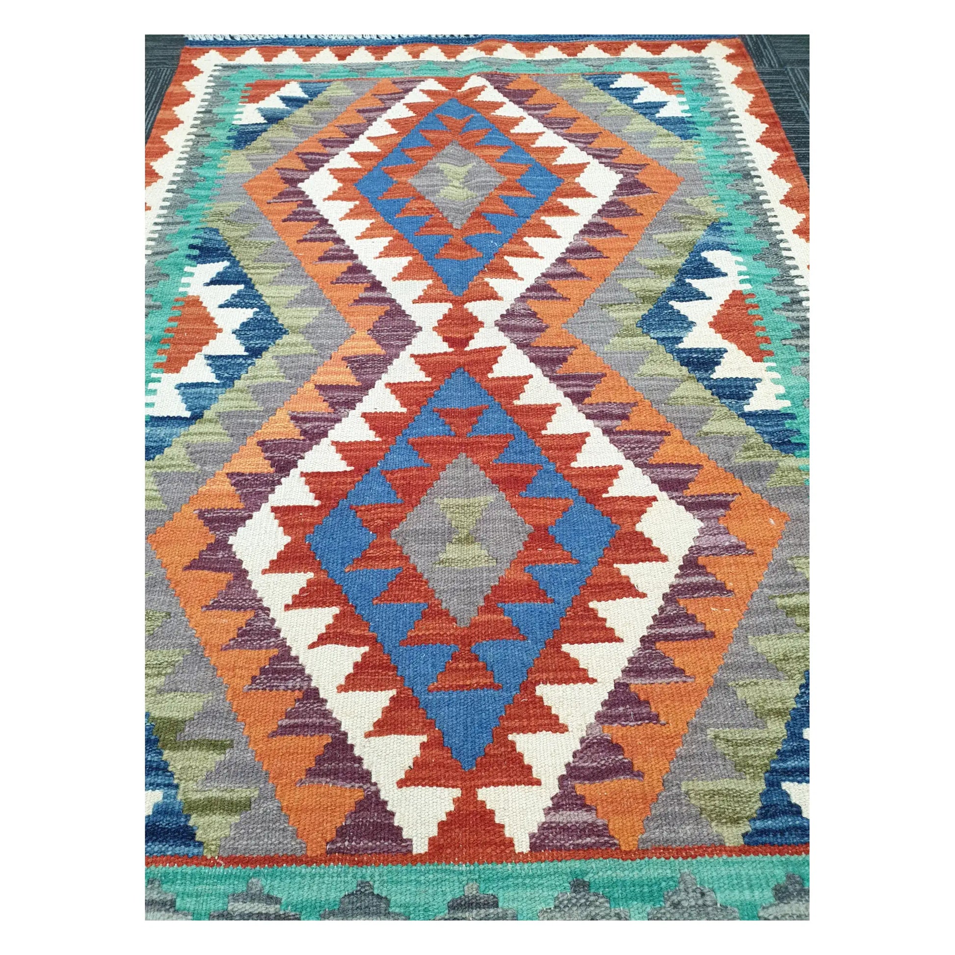 Close-up of Chobi Kilim rug with stacked medallions in terracotta, blue, teal, and ivory, 119 x 84 cm