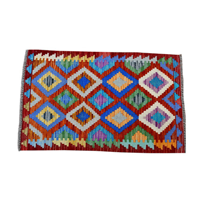Top view of Afghan Chobi Kilim rug with burgundy-red field, orange lattice and multicolour diamond motifs