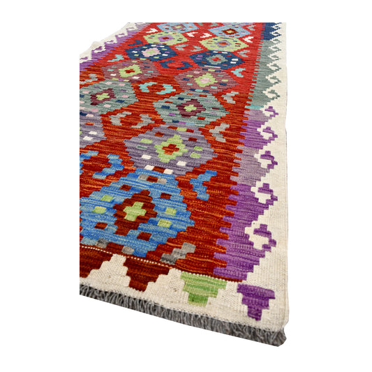 Angled corner detail of Afghan Chobi Kilim runner showing a sky-blue medallion, stepped ivory border and multicoloured edge motifs