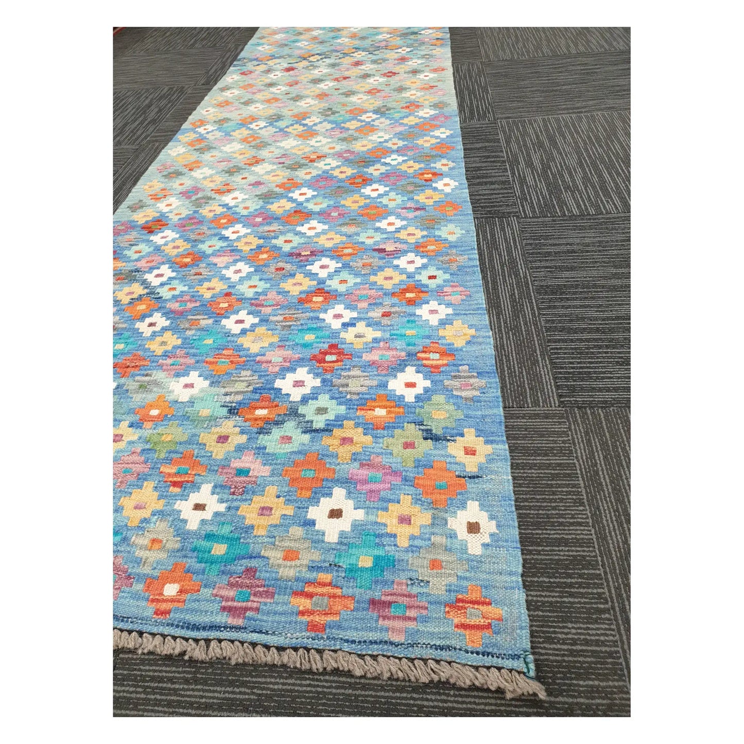 Angled view of Afghan Chobi Kilim runner showing floral diamond grid pattern and fringe, 303 x 80 cm