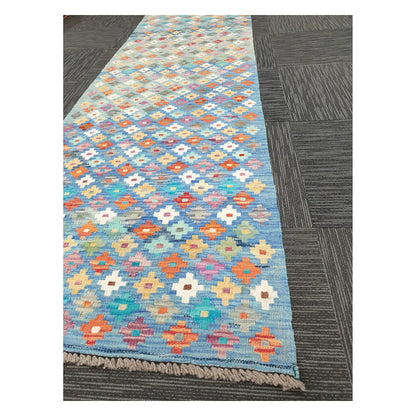 Angled view of Afghan Chobi Kilim runner showing floral diamond grid pattern and fringe, 303 x 80 cm