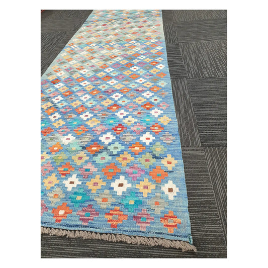 Angled view of Afghan Chobi Kilim runner showing floral diamond grid pattern and fringe, 303 x 80 cm