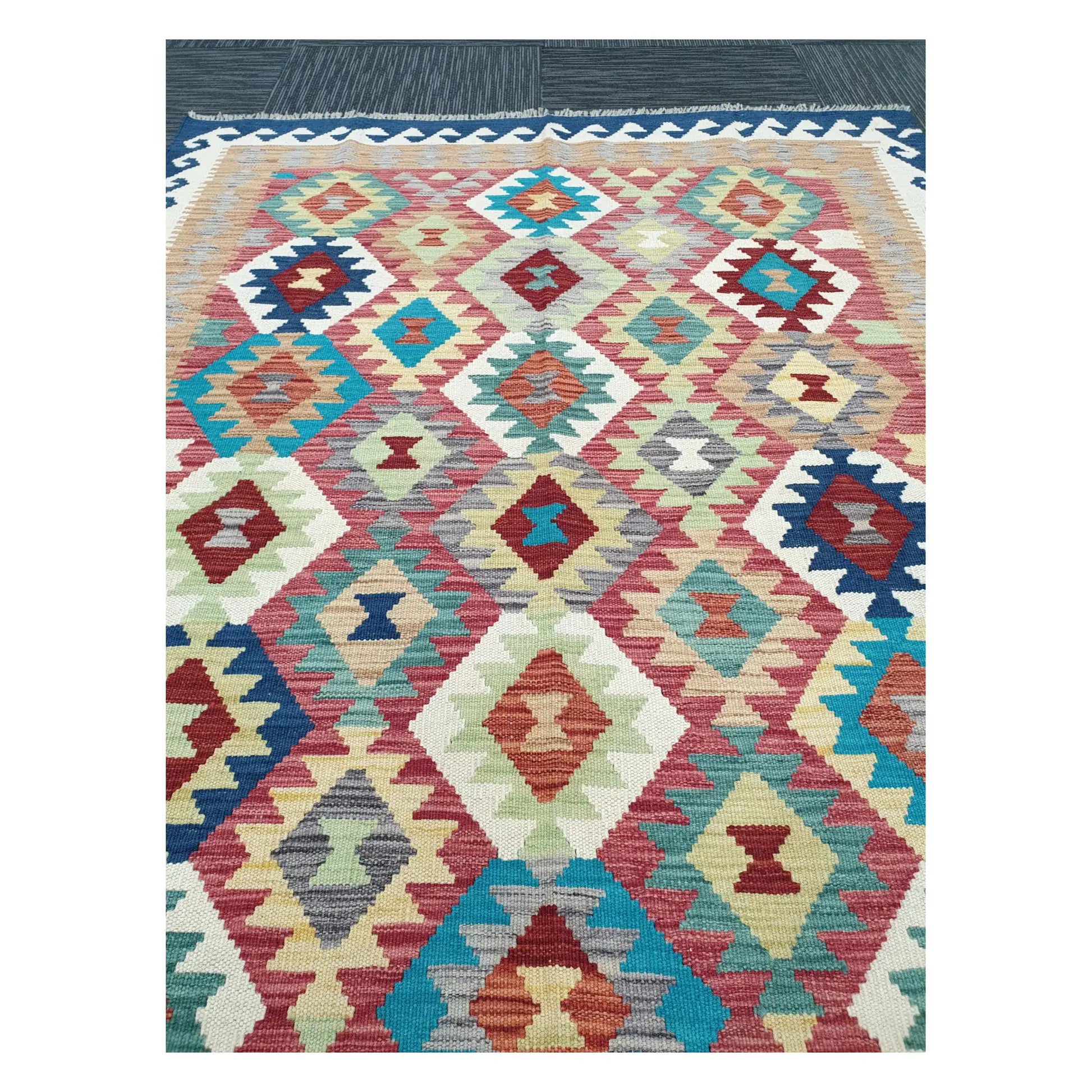 Close-up of Chobi Kilim rug with repeating diamond motifs in turquoise, rust, coral, and soft blue, 178 x 128 cm