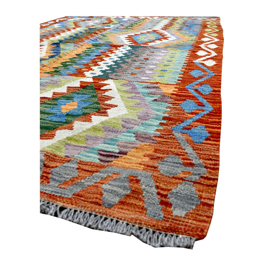 Angled corner detail of the Afghan Chobi Kilim rug showing its terracotta border, pale blue motifs and ivory fringe.