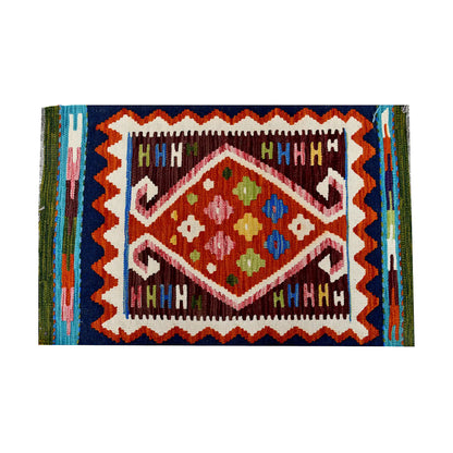 Close-up of Afghan Chobi Kilim wool rug showing burgundy framed diamond medallion with ivory, teal and olive details