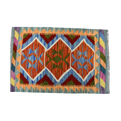 Close-up of Afghan Chobi Kilim wool rug showing rust and blue medallion design with zigzag outlines and colourful border motifs