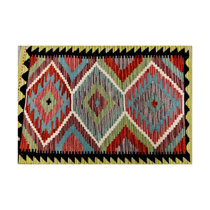 Close-up of Afghan Chobi Kilim wool rug showing sage green and soft blue field with rust-orange diamond motifs and black border detail