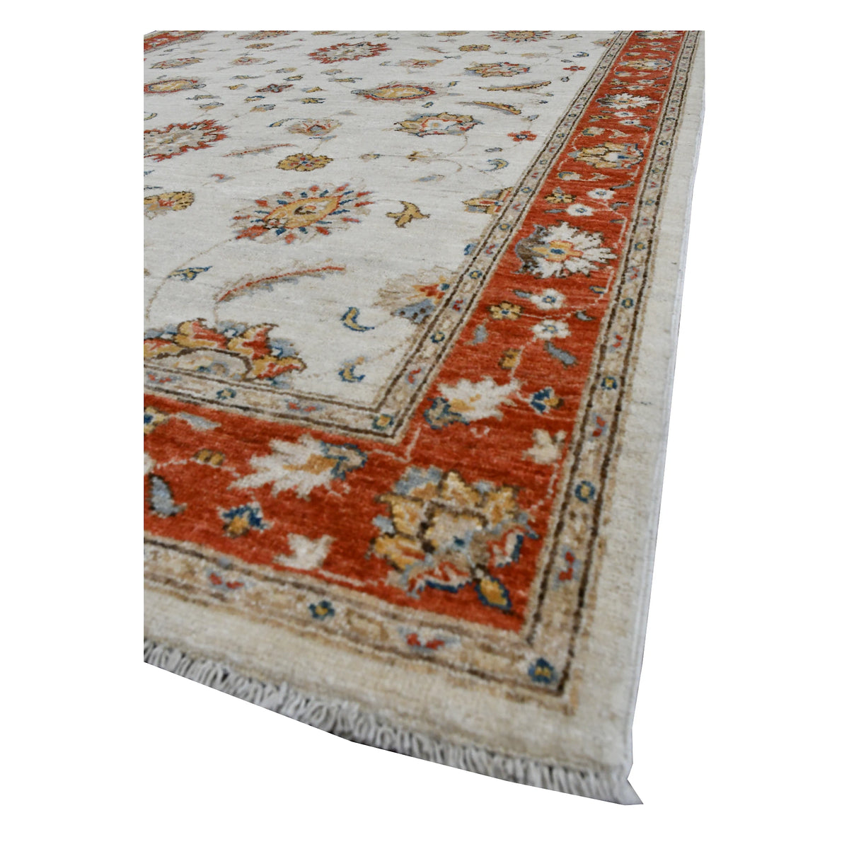 Angled view of Afghan Chobi wool rug showing its off-white floral field, rust-red border and pale fringe