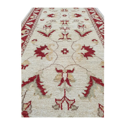 Field detail of Afghan Chobi runner showing beige floral vine pattern and red border