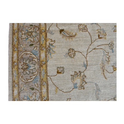 Close-up of Afghan Chobi soft beige rug showing the pale blue and gold floral border beside the open field with delicate vine motifs