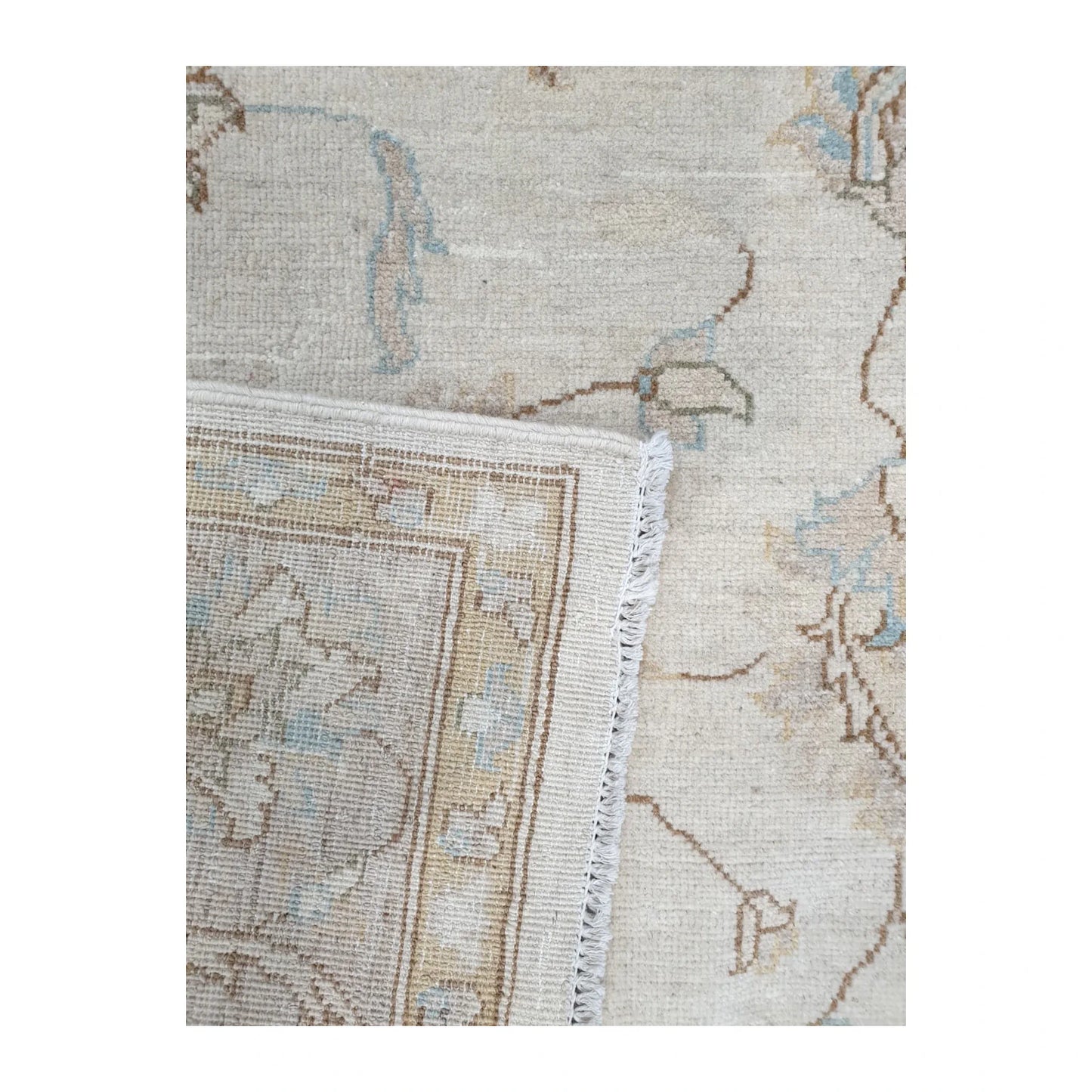 Folded corner detail of Afghan Chobi rug showing the reverse weave, ivory fringe and layered floral border
