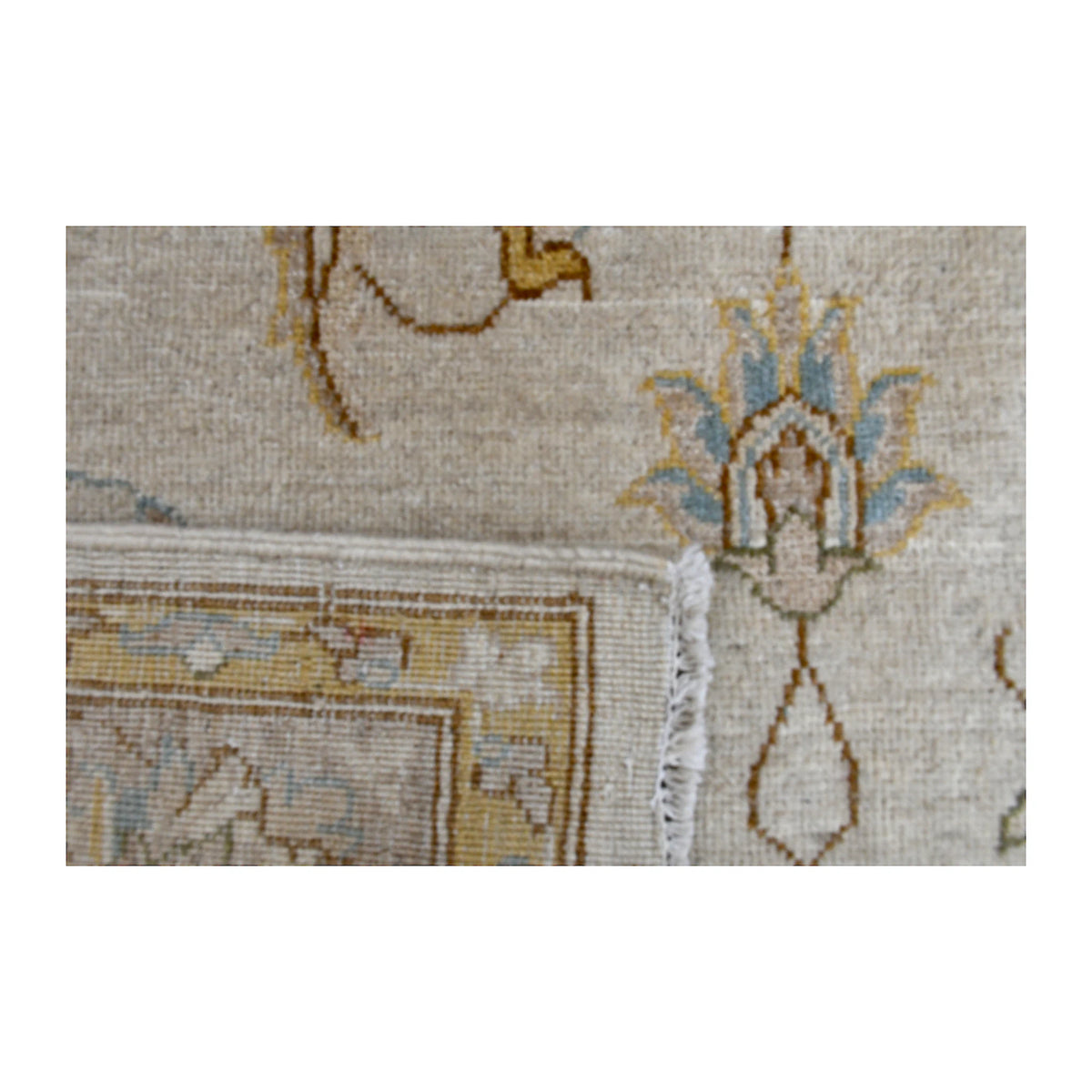 Folded corner detail of Afghan Chobi rug showing the reverse weave, ivory fringe and layered floral border