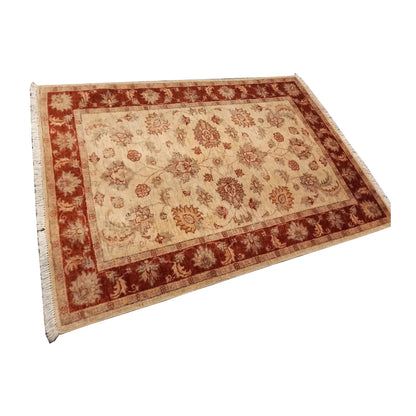 Angled full view of the Afghan Chobi rug showing its open floral field and broad rust-red border
