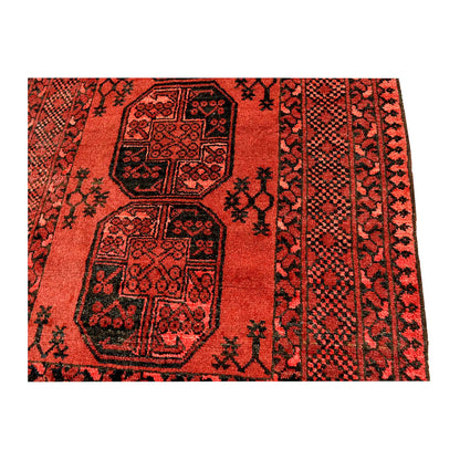Field and border detail of Afghan Ersari hand-knotted wool rug showing central medallions and dark geometric patterning