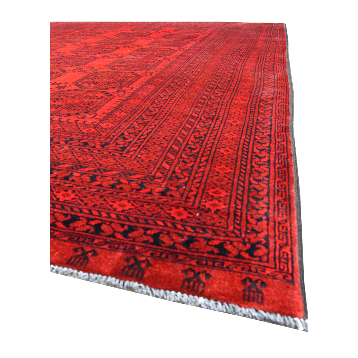 Angled view of Afghan Ersari wool rug showing its tonal red gul field, layered tribal borders and pale fringe