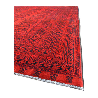 Angled view of Afghan Ersari wool rug showing its tonal red gul field, layered tribal borders and pale fringe