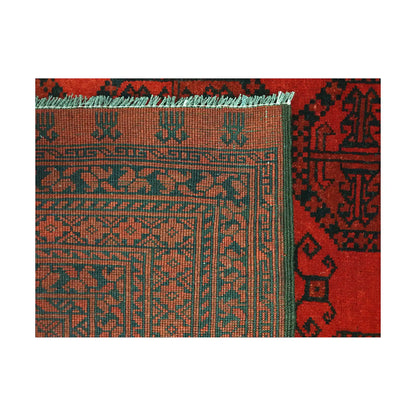 Folded corner detail of Afghan Ersari rug showing the back of the rug, fringe and tonal red front pattern