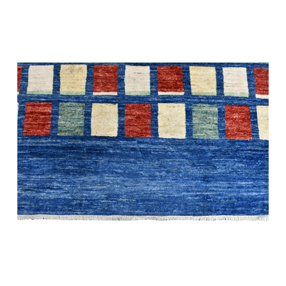 Fringed end of the blue Gabbeh rug beneath rows of ivory, rust and sage blocks