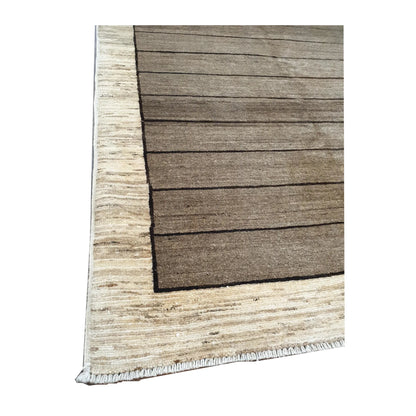 Angled view of Afghan Gabbeh hand-knotted wool rug showing natural wool texture, light brown field and cream border, 166 x 106 cm